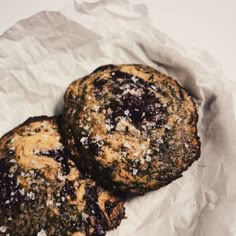 two chocolate chip cookies sitting on top of white paper covered in flecky sugar