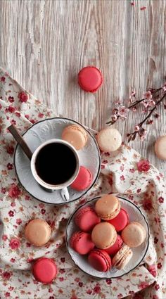 two plates filled with macaroons next to a cup of coffee on a table