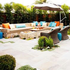 an outdoor living area with couches, tables and umbrellas in the middle of it