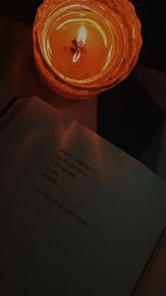 a lit candle sitting on top of an open book