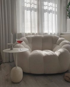 a living room filled with furniture and a wine glass on top of a small table