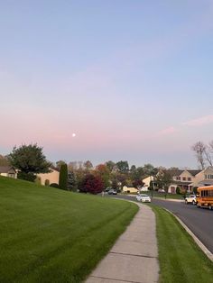 a yellow school bus driving down a street next to a lush green field and houses