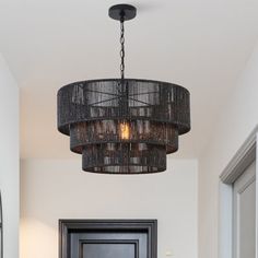 an entryway with a black door and chandelier hanging from it's ceiling