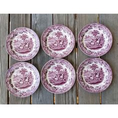 six pink and white plates sitting on top of a wooden table