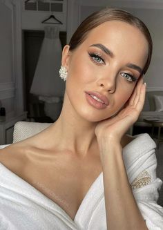 a woman in a white dress posing for the camera with her hand on her chin