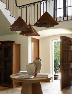 a table with some vases on top of it in front of a spiral staircase