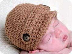 a baby wearing a brown crochet hat with a button on it's side