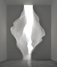 an abstract white sculpture in a room with light coming through the window and onto the floor