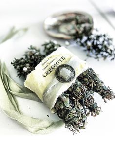 a pile of green tea sitting on top of a white table next to two spoons