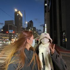 two women walking down the street at night wearing face masks to protect them from the sun