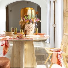 a dining room table with pineapple centerpiece and orange napkins on the table