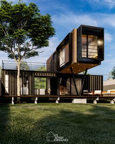 a house made out of shipping containers sitting on top of a lush green field next to a tree