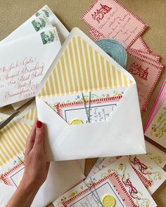 a person is opening an envelope on top of some cards and paper with scissors in it