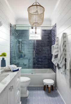 a blue tiled bathroom with white fixtures and wood accents on the walls, along with a wooden basket hanging from the ceiling