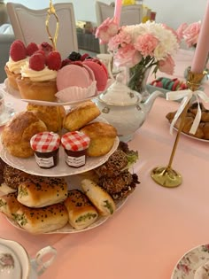 three tiered trays filled with pastries and desserts on a pink table cloth