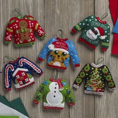 christmas sweaters and mittens are hanging on a wooden table next to folded napkins