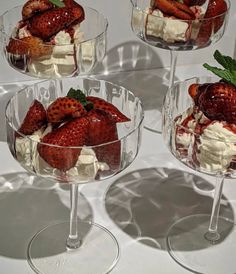 four dessert dishes with strawberries and whipped cream