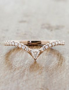 a white gold wedding band with three diamonds on the top and bottom, sitting on a wooden surface