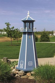 a green and white lighthouse sitting in the middle of a field