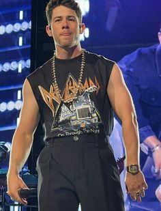 a male in a black shirt and pants on stage with his hands in his pockets