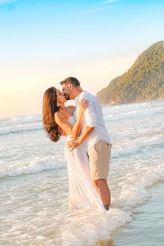 a man and woman kissing in the ocean