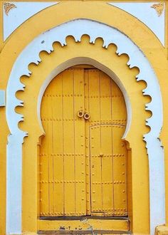 an old yellow door with white trim and arches