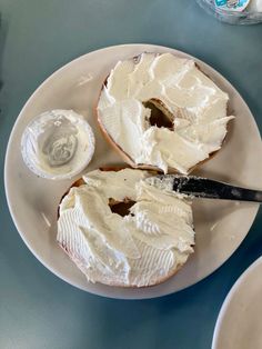 a plate with two pieces of bread and cream cheese on it next to a bottle of water