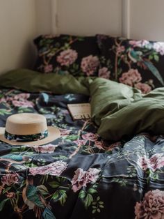 an unmade bed with green and pink flowers on the comforter next to it