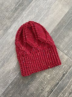 a red knitted hat sitting on top of a wooden floor