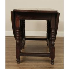 an old wooden table with carved legs and a drawer on the top, sitting on a hard wood floor