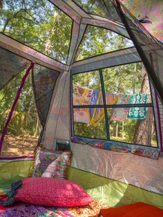 the inside of a tent with pillows and blankets on it's sides, in front of a large window