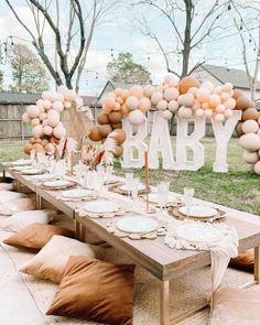 an outdoor baby shower is set up with balloons, plates and napkins on the table