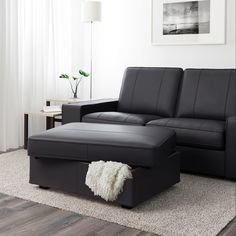 a living room with a black leather couch and footstool next to a white rug