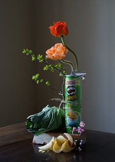 an arrangement of flowers in a can and other items on a table with a gray background