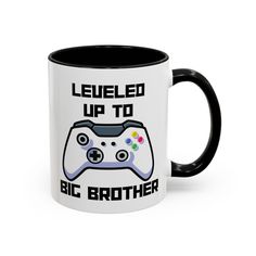 a black and white coffee mug with a game controller printed on the side that says, fueled up to big brother