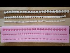 three different shapes and sizes of plastic beads on a wooden surface with one being white, the other is pink