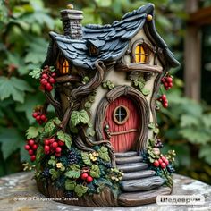 a small house made out of clay with berries and leaves on the outside, sitting on top of a rock