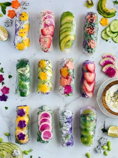 there are many different types of sushi on the table with fruit and cucumbers