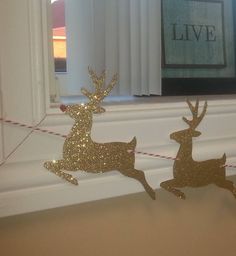 two gold glitter deer decorations on a window sill