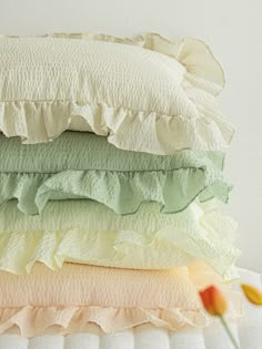 four pillows stacked on top of each other with ruffles and one flower in the foreground