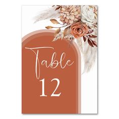 an orange table number card with flowers and feathers on the front, reads table 12