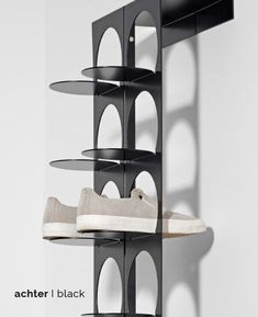 a pair of shoes is sitting on a shelf in front of a white wall with the words, achter i black