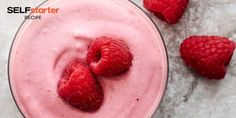 raspberry smoothie in a glass with strawberries on the side