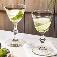 two glasses filled with green liquid and lime slices