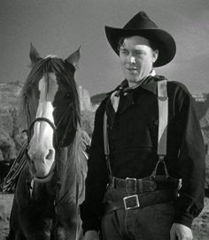 a man standing next to a horse wearing a cowboy hat