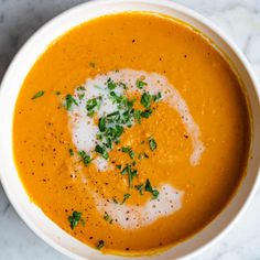 a white bowl filled with soup and garnished with parsley