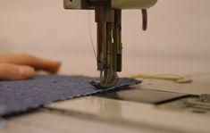 someone is using a sewing machine to sew something on a piece of blue fabric