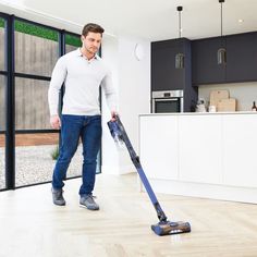 a man is cleaning the floor with a vacuum mop in his hand and looking at the camera