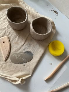 two bowls and spoons sitting on top of a piece of cloth next to some wooden utensils