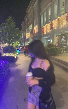 a woman is walking down the street at night